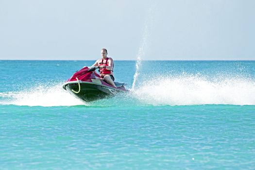 Young guy cruising on a jet ski on the caribbic sea