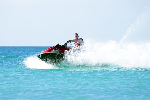 Young guy cruising on a jet ski on the caribbic sea