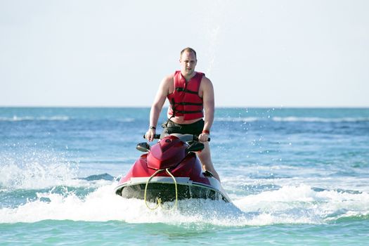 Young guy cruising on a jet ski on the caribbic sea