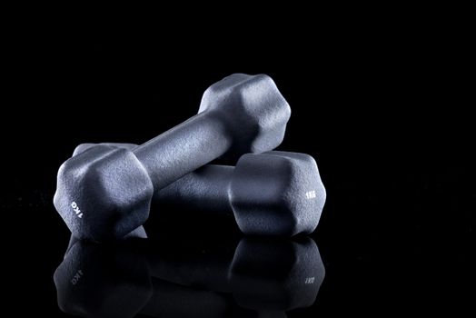 One kilogram dumbbells for weight training on black background.