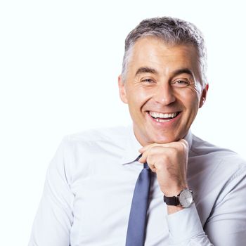 Confident businessman smiling with hand on chin and looking at camera on white background.