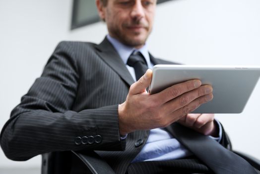 Smiling businessman working with tablet in his office, hand close up.