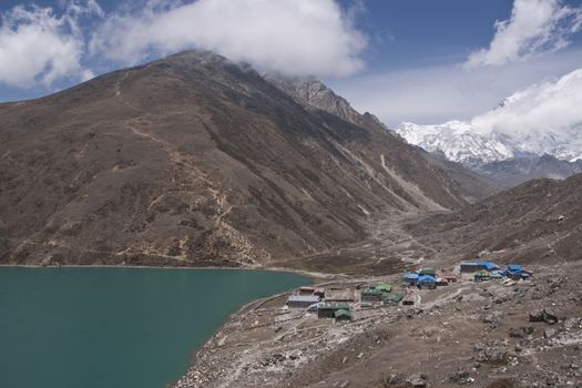 Mountains surrounding the clear blue waters of Gokyo Lake and the small village of Gokyo, 4700 meters up in the Himalaya Mountains of Nepal.