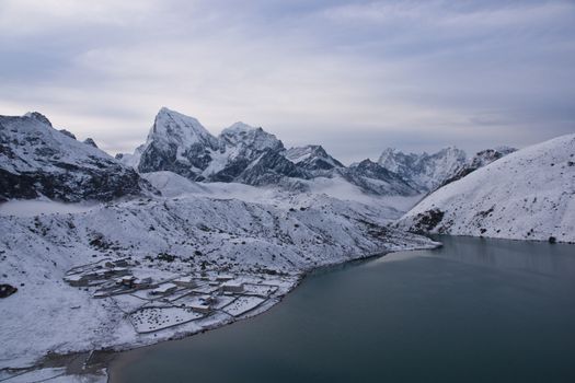 Snow covered village of Gokyo on the shore of Gokyo lake 4800 meters up in the Himalaya Mountains of Nepal. Ngozumpa Glacier flows behind the village.