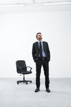 Smiling businessman standing in his new empty office with hands in pockets looking around.