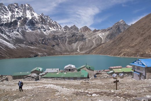 Buildings in the village of Gokyo next to a still lake and surrounded by mountains 4800 meters up in the Himalaya Mountains of Nepal.