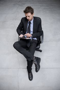 Businessman working with tablet on concrete floor background.