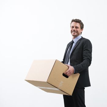 Smiling businessman holding a cardboard box and standing into an empty new office.