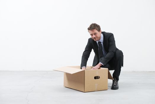 Businessman looking around and packing with cardboard box in an empty office.