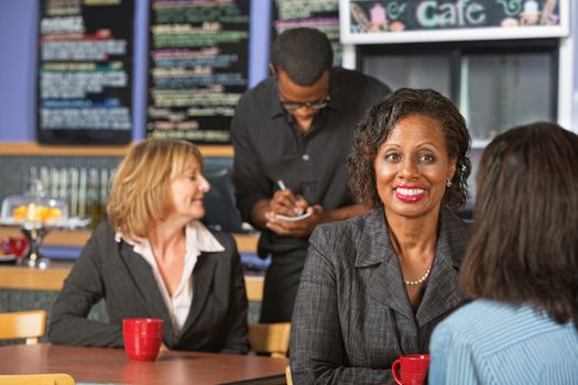 Mature smiling business woman with friend in cafe