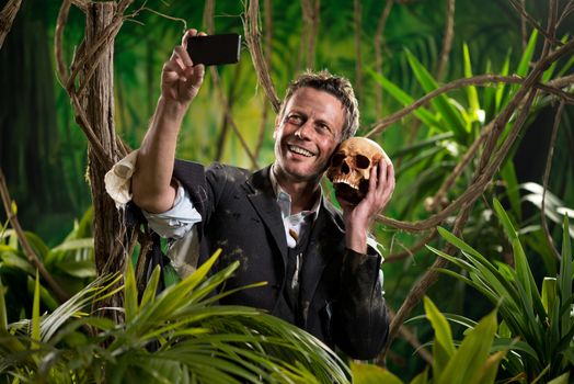 Businessman in the jungle taking a self portrait with human skull.