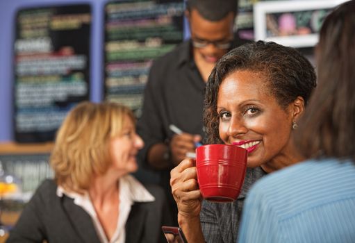 Cheerful business woman sipping beverage in cafe
