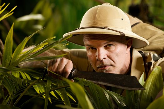 Survival confident adventurer exploring the rainforest jungle holding a machete.