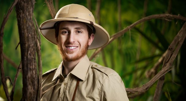 Young confident explorer in the jungle with pith hat smiling at camera.