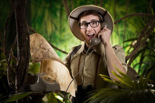 Young retro explorer asking informations in the jungle with vintage telephone and map.