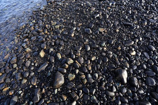 Colorful pebbles touching wave at beautiful rock island, called Koh Hin Ngam, near Lipe island, Thailand