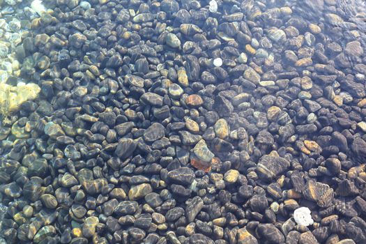 Colorful pebbles touching wave at beautiful rock island, called Koh Hin Ngam, near Lipe island, Thailand