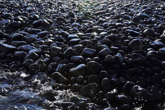 Colorful pebbles touching wave at beautiful rock island, called Koh Hin Ngam, near Lipe island, Thailand