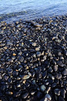 Colorful pebbles touching wave at beautiful rock island, called Koh Hin Ngam, near Lipe island, Thailand