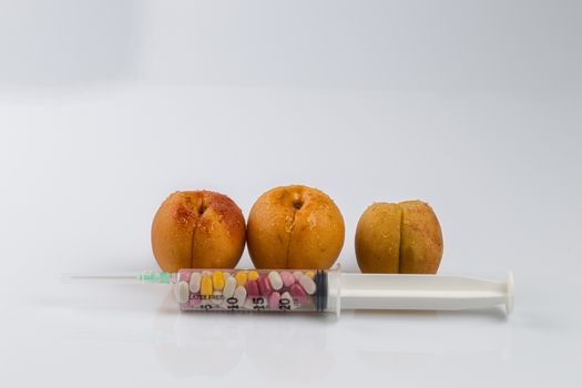 Female menopause and sexual disease metaphor: peaches and syringe with pills meaning cosmetic and health treatment for female ageing