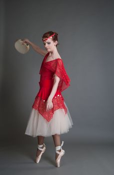 dancer in a red dress with a tambourine in Pointe on a grey background