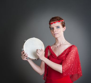 dancer in a red dress with a tambourine in Pointe on a grey background