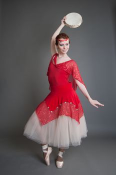dancer in a red dress with a tambourine in Pointe on a grey background