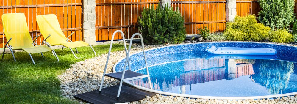 panorama of small home swimming pool with yellows sun loungers