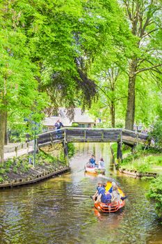 Unknown visitors in the boating in a canal in Giethoorn. The city is know as "Venice of the North" and has over 150 bridges.