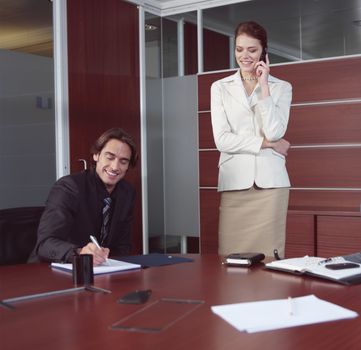 confident employees looking at monitor while their boss talking by phone 