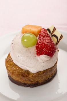 Gourmet creamy dessert with a chocolate and cake base topped with fresh fruit and a chocolate wafer served on a plate in vertical format with copyspace