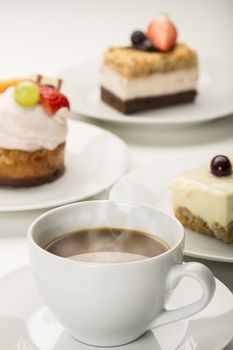 Hot freshly brewed cup of aromatic coffee served with a variety of cakes or pastries in a restaurant, for a coffee break or when entertaining at a party