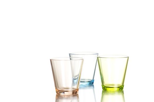 Three shot glasses colored brown, blue and green on white background