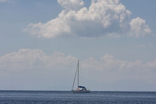 Lonely sailboat sails slowly expecting better wind