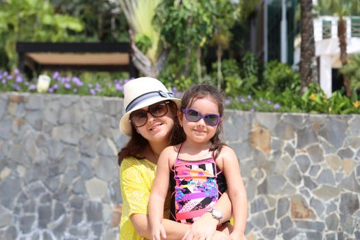 Mother and daughter enjoying the summer outdoors with fancy sunglasses. Focus in the little girl.