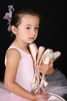 Cute brunette ballet girl holding lots of pointe shoes 