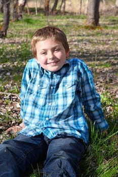 Young boy sitting outside in the field relaxing