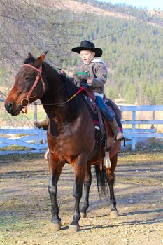 Young cowboy riding his horse on the farm