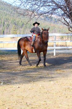 Young cowboy riding his horse on the farm