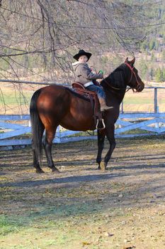 Young cowboy riding his horse on the farm
