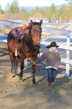 Young cowboy walking his horse on the farm