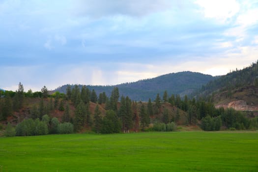 Green hayfields against mountain and dark stormy skies