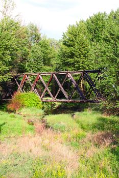 Old bridge in spring forest crossing water