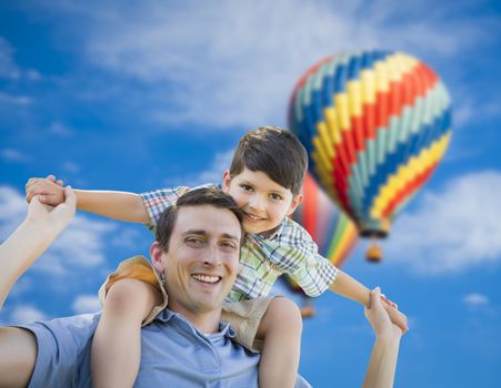 Father and Son Playing Piggyback with Hot Air Balloons Floating Behind Them.