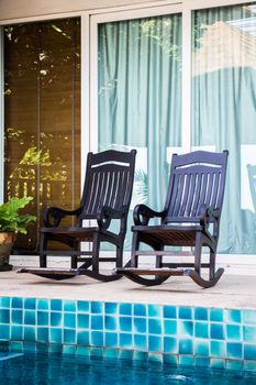 Wooden arm chairs beside the pool, stock photo