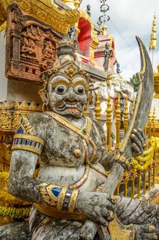 The giant protector with sword in front of the Thai temple.