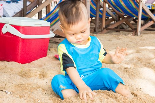 Asian boy playing sand on the beach, stock photo