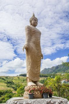 the gold buddha statue standing under the sun and blue sky at Thai temple