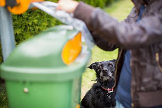 Do not let your dog faul! - Young woman grabbing a plastic bag in a park to tidy up after her dog later