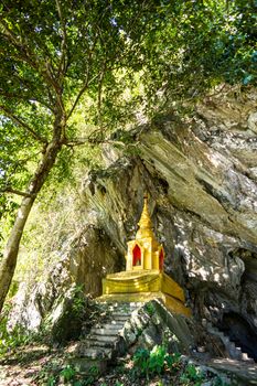 golden pagoda infront of natural cave in the forest,Chiangrai,Thailand